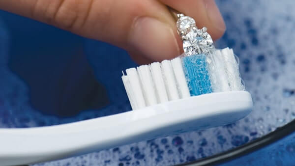 Поместив украшение с бриллиантом в мыльный раствор, аккуратно почистите камень мягкой зубной щеткой